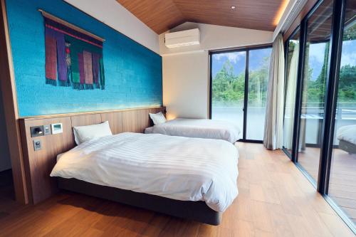 a bedroom with two beds and a large window at ICHIFUJI Ryokan in Hitoyoshi