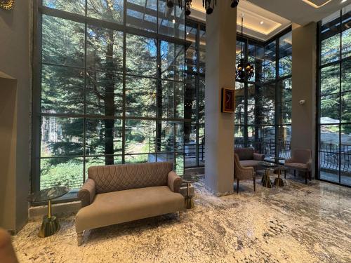 a living room with a couch and large windows at Mastiff Select Mandavya Dharamkot, McLeodganj in Dharamshala