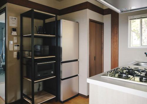 a kitchen with a white refrigerator and a stove at Tsugumori つぐもりステイ in Komoro