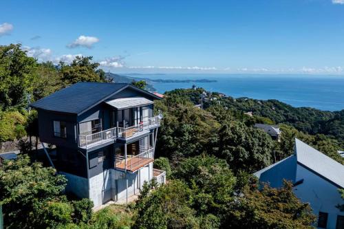 a house on a hill with the ocean in the background at The Villas atami amazing ocean view in Taga