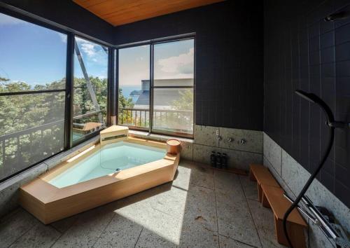 a bathroom with a tub in a room with windows at The Villas atami amazing ocean view in Taga