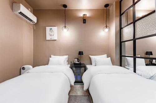 two beds in a room with white sheets at Seosan No25 Hotel in Seosan