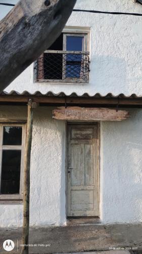 a white building with a door and a window at Alquilo casa en las Sierras de Minas "VIEJO RANCHO" in Minas