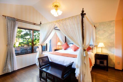 a bedroom with a canopy bed and a window at Coco Garden Resort Okinawa in Uruma