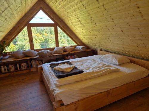 a bed in a wooden room with a large window at Bacmańska Chata z pięknym widokiem przy szlaku jacuzzi Beskidy in Złatna