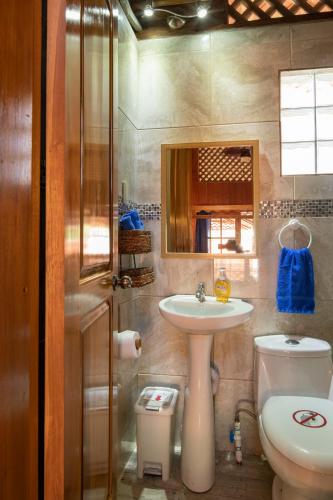 a bathroom with a sink and a toilet and a mirror at Pangea Lodge with Shared Pool at the Heart of Manzanillo in Manzanillo