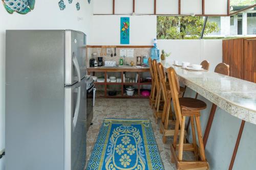 a kitchen with a refrigerator and a counter with chairs at Pangea Lodge with Shared Pool at the Heart of Manzanillo in Manzanillo
