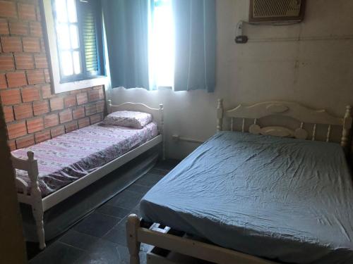 two beds in a room with two windows at Casa de Praia em Itamaracá in Vila Velha