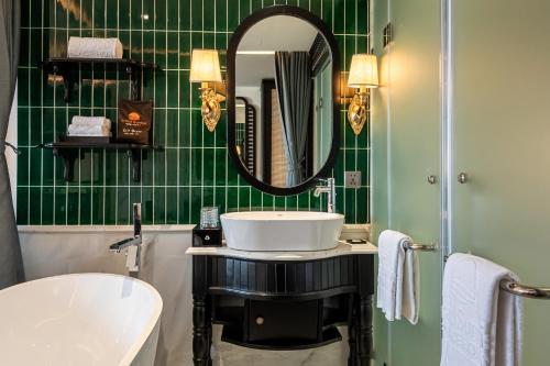 a green tiled bathroom with a sink and a mirror at Grand Sunrise Palace Hoi An- A Luxury Indochine Hotel & Spa in Hoi An