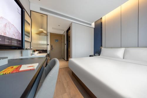 a bedroom with a large white bed and a desk at Atour Hotel Beijing Temple of Heaven East Gate Longtan Park in Beijing