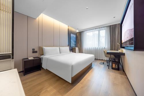 a hotel room with a white bed and a desk at Atour Hotel Beijing Temple of Heaven East Gate Longtan Park in Beijing