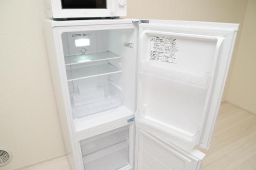 a white refrigerator with its door open in a kitchen at NYHotel 3 新宿2階建て3室1バスルーム1シャワー2トイレ in Tokyo