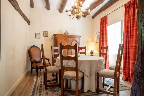 une salle à manger avec une table, des chaises et un lustre dans l'établissement Les Demeures du Tonnelier ''La Maison Pini'', à Saint-Romain