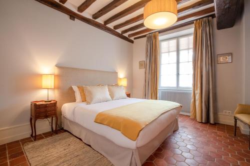 Un dormitorio con una cama grande y una ventana grande. en Les Demeures du Tonnelier ''La Maison Pini'', en Saint-Romain