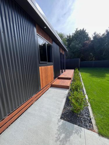 a house with a walkway next to a building at Cosy Apartment with Outdoor Private Bath for 2 in Timaru