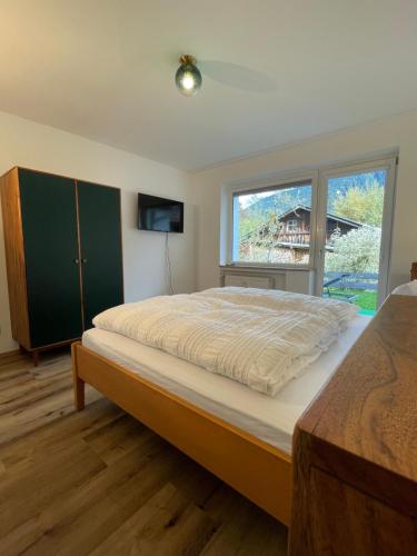 a bedroom with a large bed with a large window at Ferienwohnung mit Terrasse und Garten mit Blick auf das Karwendelgebirge in Mittenwald
