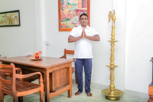 a man in a white shirt standing next to a table at Prana Ayurveda Yoga Center in Balapitiya
