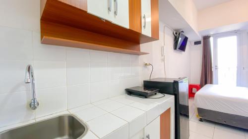 eine Küche mit Spüle und ein Bett in einem Zimmer in der Unterkunft Comfortable Studio Room at Tokyo Riverside Apartment By Travelio in Rawalembang