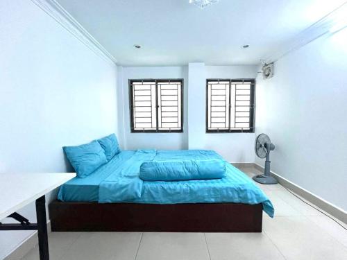 a bedroom with a bed with blue sheets and two windows at The Moonvine on 360 in Phnom Penh