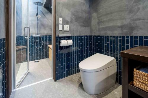 a bathroom with a toilet and a shower with blue tiles at Ichika Machiya House in Takayama