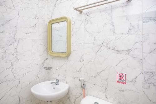 a white bathroom with a sink and a mirror at Sans Hotel City Park Medoho Semarang in Alastuwo