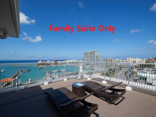 a balcony with two chairs and a view of the ocean at Seaside Condominium Rana Chatan in Chatan