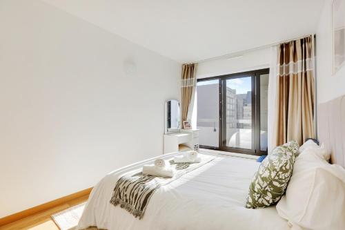 une chambre avec un grand lit blanc avec une fenêtre dans l'établissement À 1 minute du métro et Parking privé, à Paris