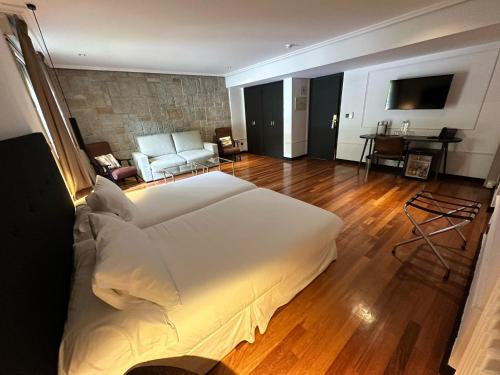 a bedroom with a large white bed and a living room at Hotel Hita "Nature Experience" for all in Navacerrada