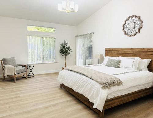a white bedroom with a large bed and a chair at Charming retreat in CA Valley in Fresno