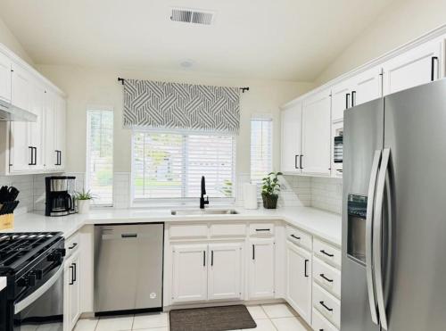 a white kitchen with white cabinets and a window at Charming retreat in CA Valley in Fresno
