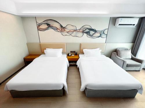 a room with two beds and a chair at 空港别墅酒店广州白云国际机场店 in Guangzhou