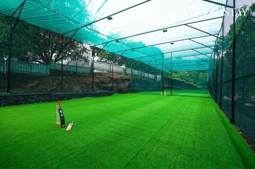 a batting cage with a green field of grass at EKOSTAY - Infinity Villa with infinity pool in Āmbavna
