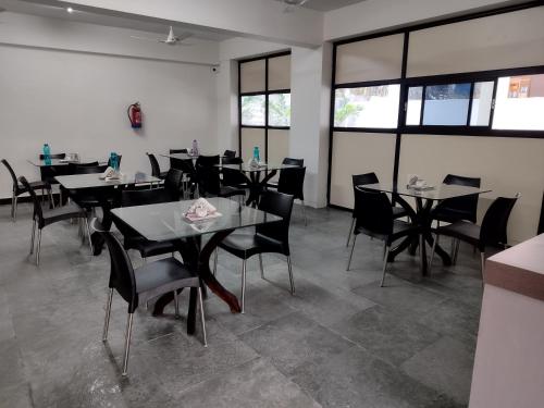 a dining room with tables and chairs and windows at Residence Retreat Service Apartments in Hyderabad