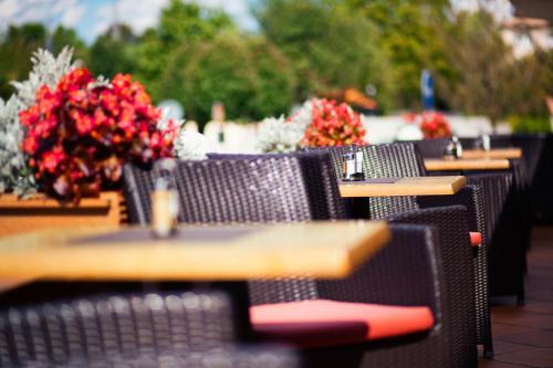 a row of tables and chairs with red flowers at Hotel Abácie & Wellness in Valašské Meziříčí