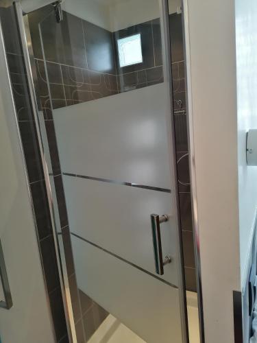 La salle de bains est pourvue d'une porte de douche en verre. dans l'établissement Bel hébergement, au Havre