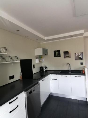 une cuisine avec des armoires blanches et un comptoir noir dans l'établissement Bel hébergement, au Havre