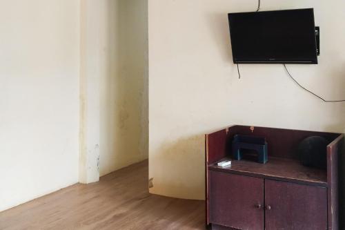 a room with a tv on a wall and a cabinet at RedDoorz at Ameria Bandara Nongsa Batam in Hang Nadim International Airport