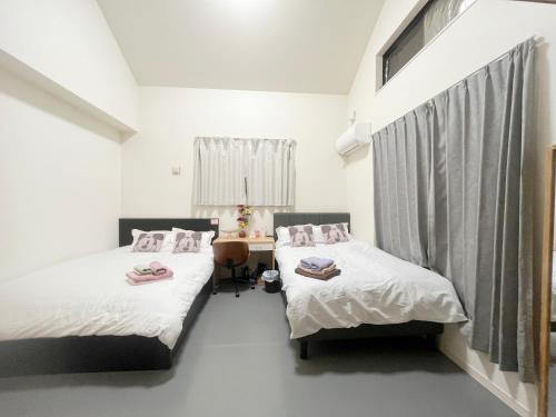 a bedroom with two beds and a desk and a window at 花乃郷 北小岩 in Tokyo