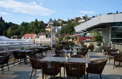 a patio with tables and chairs on a roof at Leonardo Hotel Esslingen in Esslingen