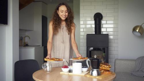 a woman standing in a kitchen with food on a table at Sea & Sun in Wierzchucino