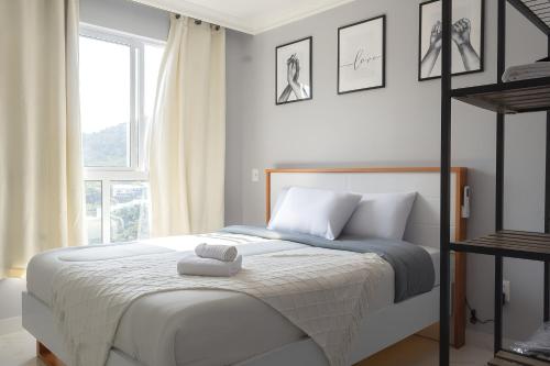 une chambre blanche avec un lit avec une fenêtre dans l'établissement Apto novo de 2 suites a 9 minutos a pe da praia, à Itapema