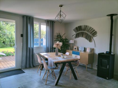 ein Esszimmer mit einem Holztisch und Stühlen in der Unterkunft Maison au calme in Bournainville
