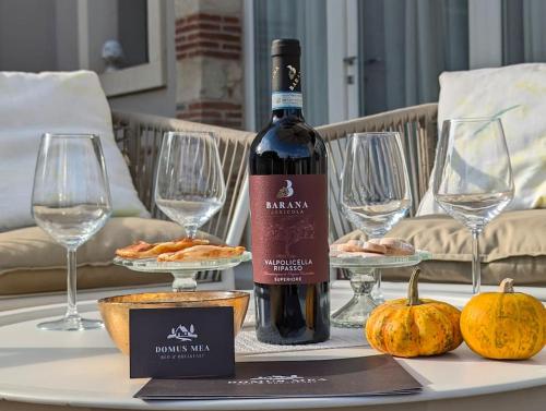 a bottle of wine sitting on a table with pumpkins at Domus MEA - Breakfast Included! in San Martino Buon Albergo
