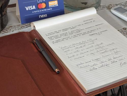a notebook with a pen sitting on a table at Domus MEA - Breakfast Included! in San Martino Buon Albergo
