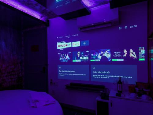a room with a purple wall with a video screen at Cupid Hotel in Ho Chi Minh City