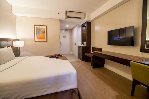 a hotel room with a bed and a television at Harolds Hotel Cebu in Cebu City
