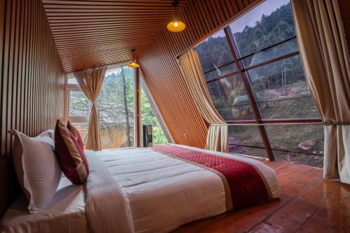 a bedroom with a large bed in front of a large window at WOW STAYZ2 Ashoka Grand in Dalhousie
