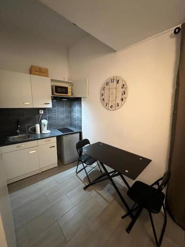 une cuisine avec une table et des chaises et une horloge au mur dans l'établissement Studio Distillerie, à Narbonne