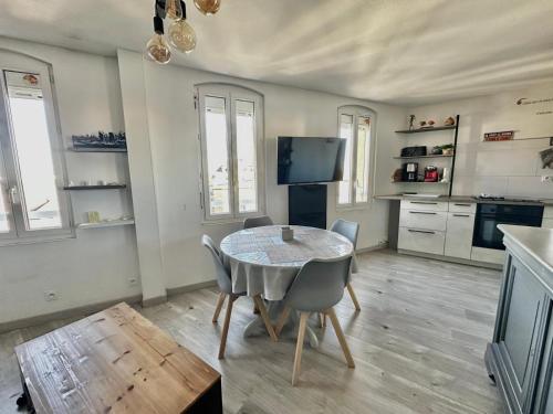 eine Küche mit Tisch und Stühlen in einem Zimmer in der Unterkunft Appartement près du port centre et plage - Vue mer in Courseulles-sur-Mer