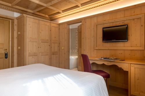 a bedroom with a bed and a tv on a wall at Hotel San Lorenzo in Bormio